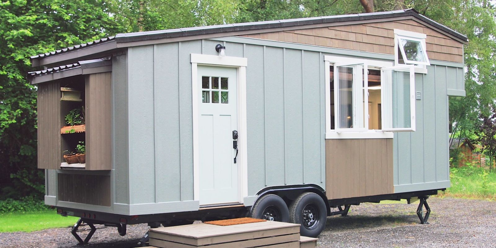 Tiny home on a trailer frame with an exterior that's grey with wood accents.
