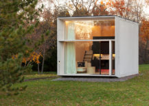 Modern tiny home with big glass front and concrete sides.