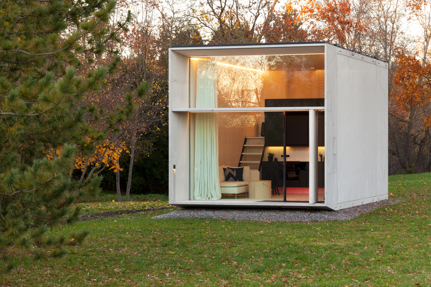 Modern tiny home with big glass front and concrete sides.
