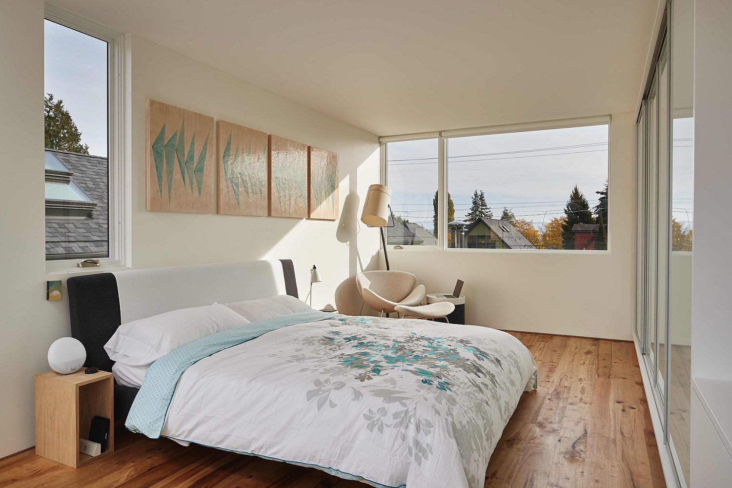 Small bedroom in white with wooden flooring and a series of windows that bring in natural light