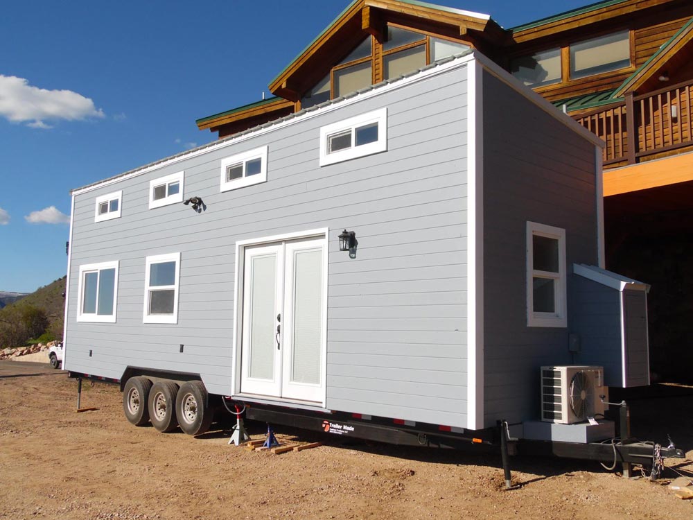 Tiny home on trailer with a grey exterior and white finishes.