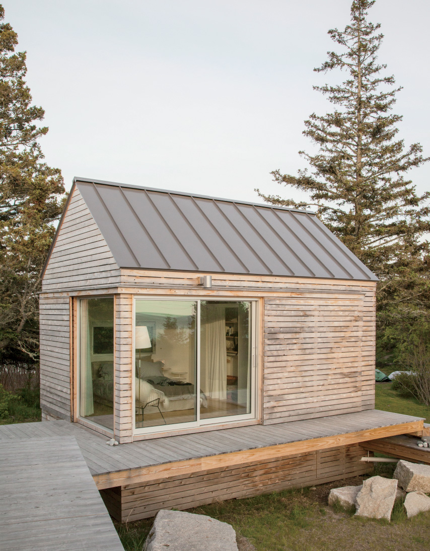 Modern tiny home with wood exterior and deck near boulders.