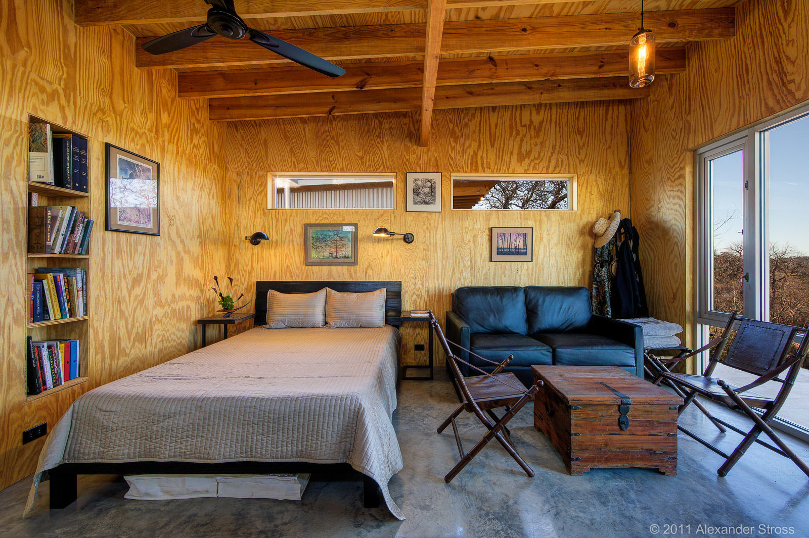 Interior of a tiny home that has wood walls and ceiling that contrast with the textured cement flooring.