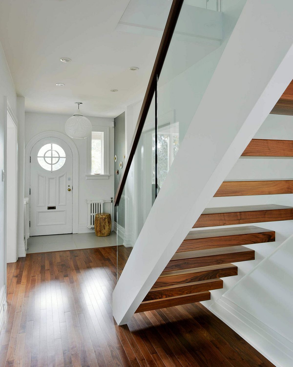 White entry and wooden stairs with glass railing at the House Addition
