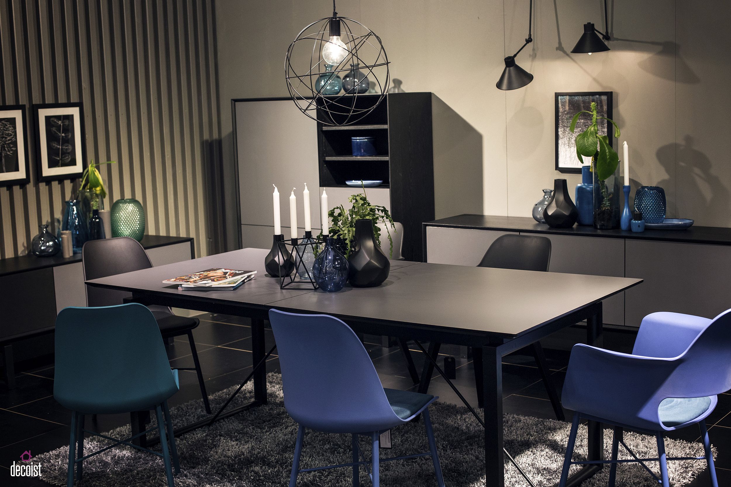 Beautiful vases in the backdrop accentuate the visual ipact of blue chairs in this black and white dining room