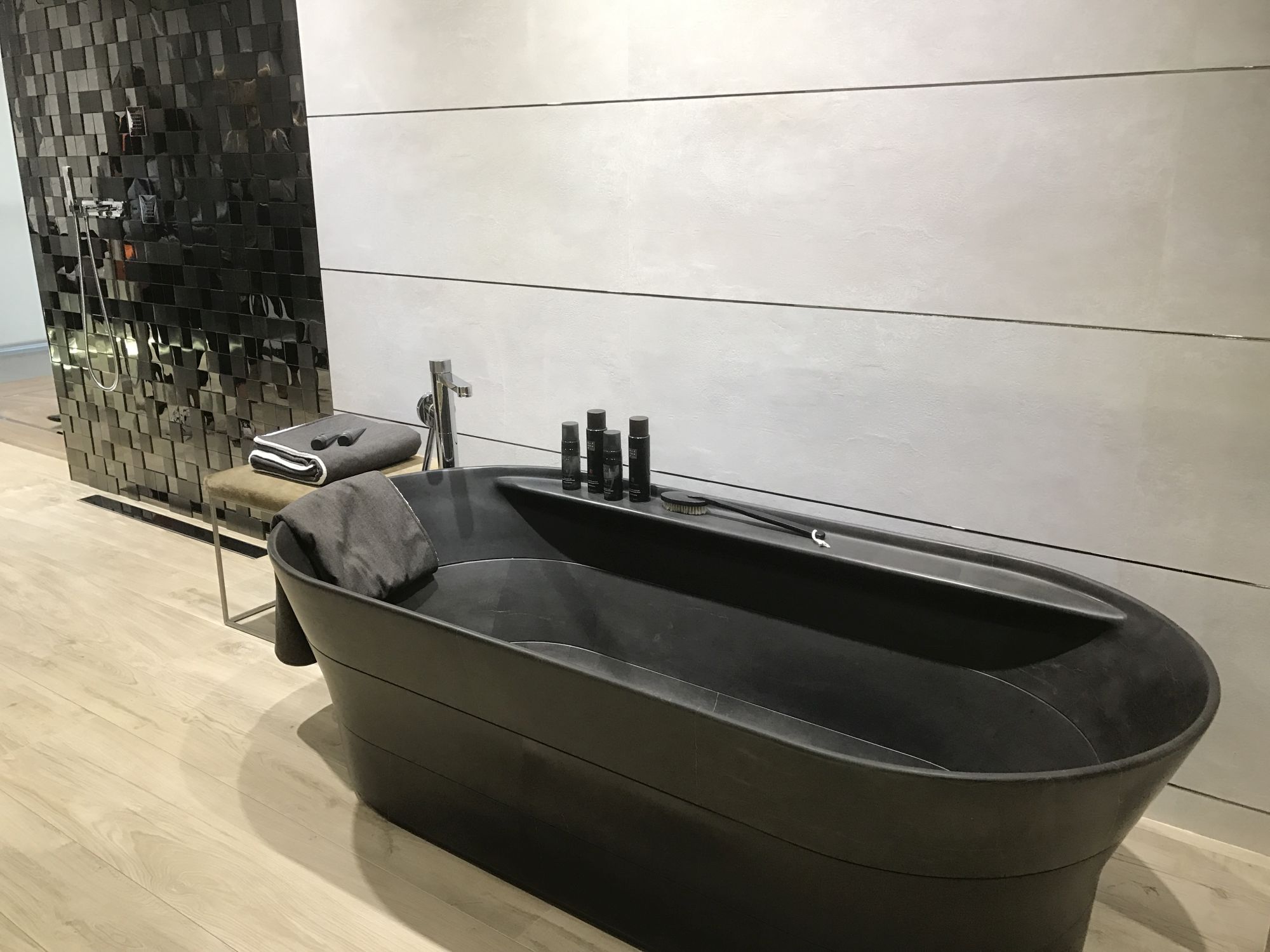 Dark stone bath tub with wood looking floor tiles by Porcelanosa