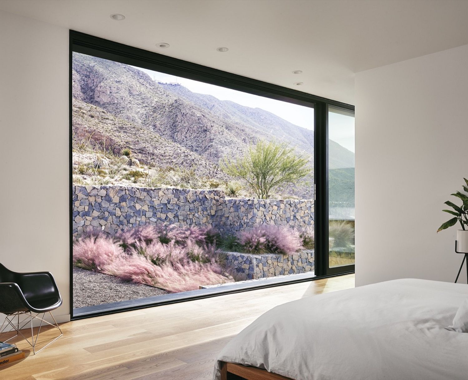 Floor-to-ceiling window connects the bedroom with the rugged mountain landscape