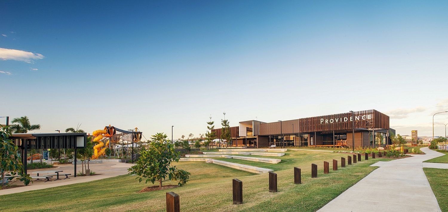 Lush green parklands and mountain views surround the neighborhood center