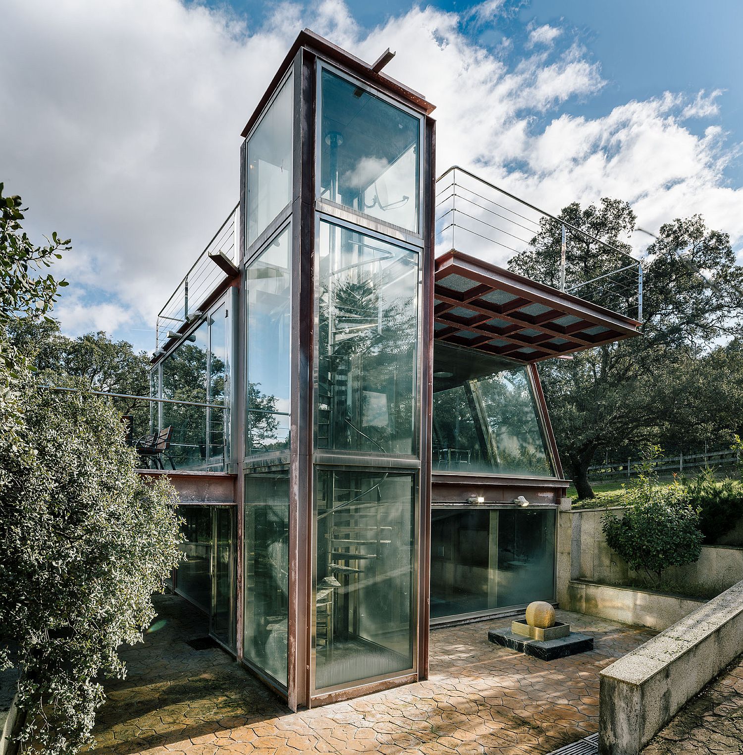 Metal-and-glass-structure-on-forest-clearing-overlooks-a-small-waterfall