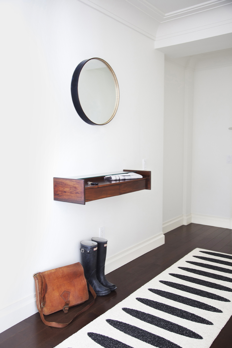 Minimalist entryway with a small mirror and a shelf