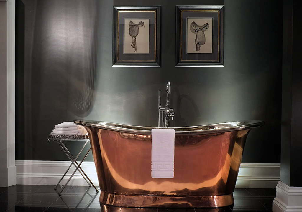 Polished and shiny copper bathtub thrives in a dark bathroom