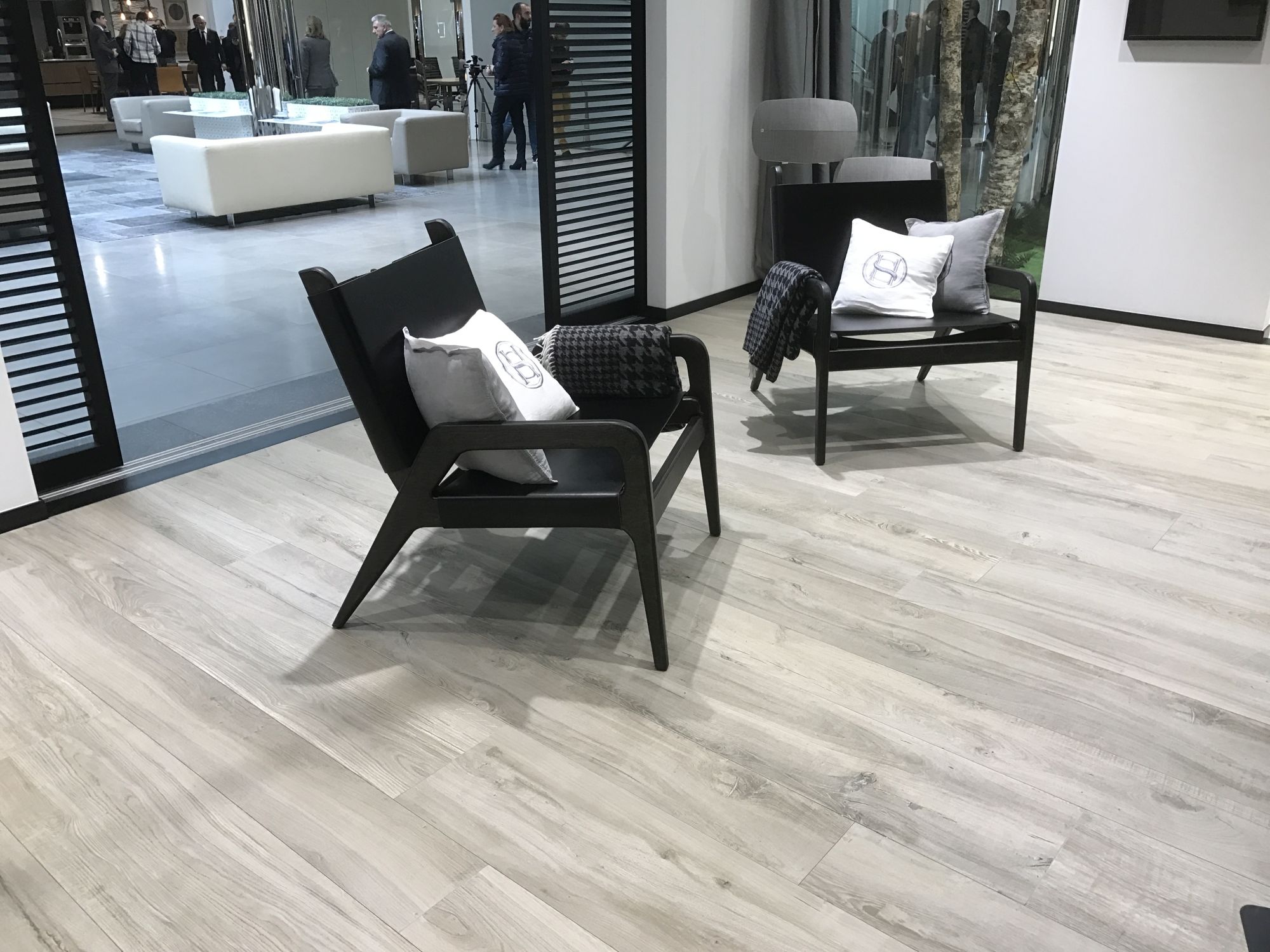 Relaxing black chairs over contrasting wood inspired floor tiles by Porcelanosa