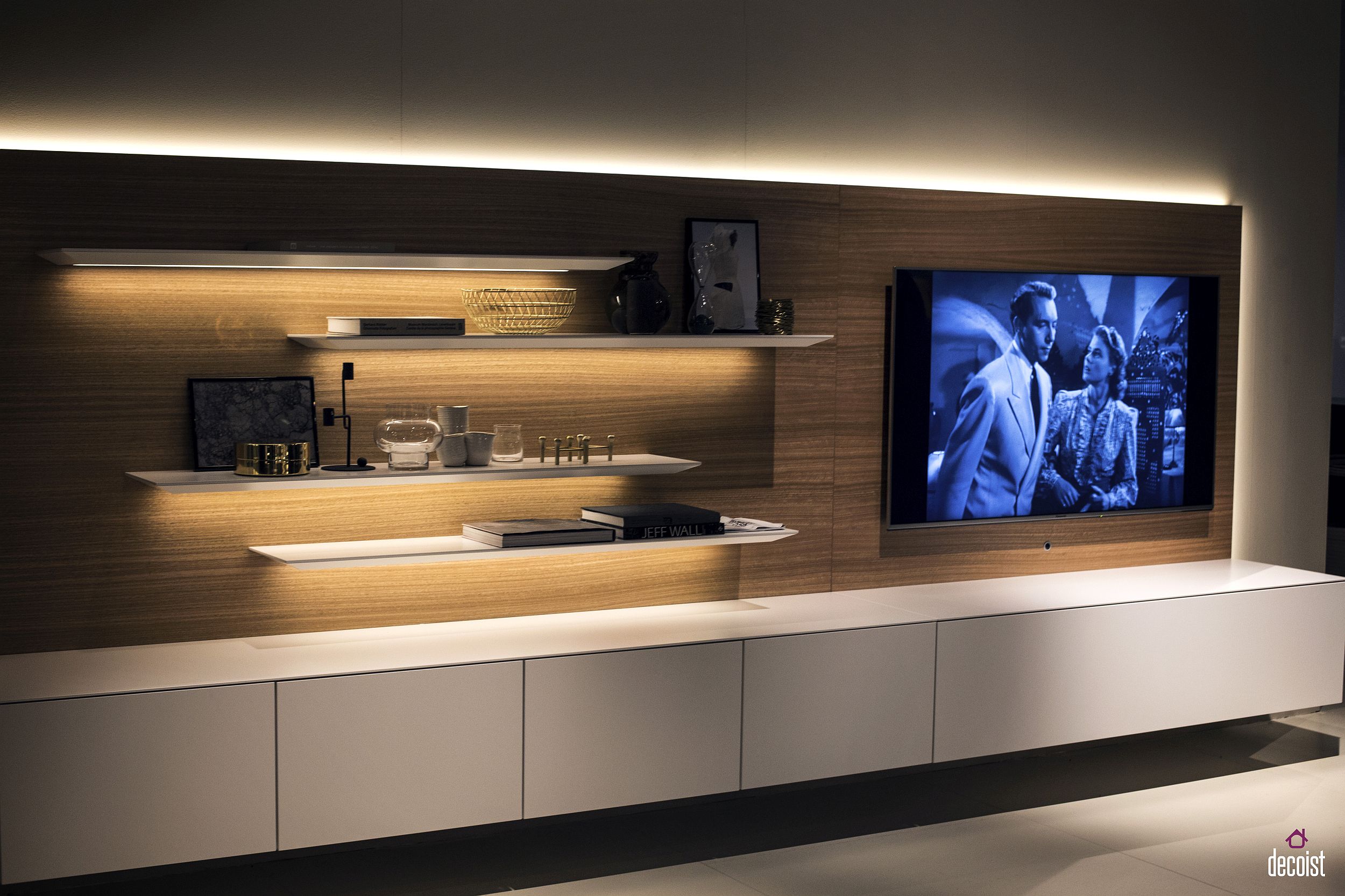 Sleek floating shelves, a backdrop clad in wood and minimal white cabinet create a stylish focal point