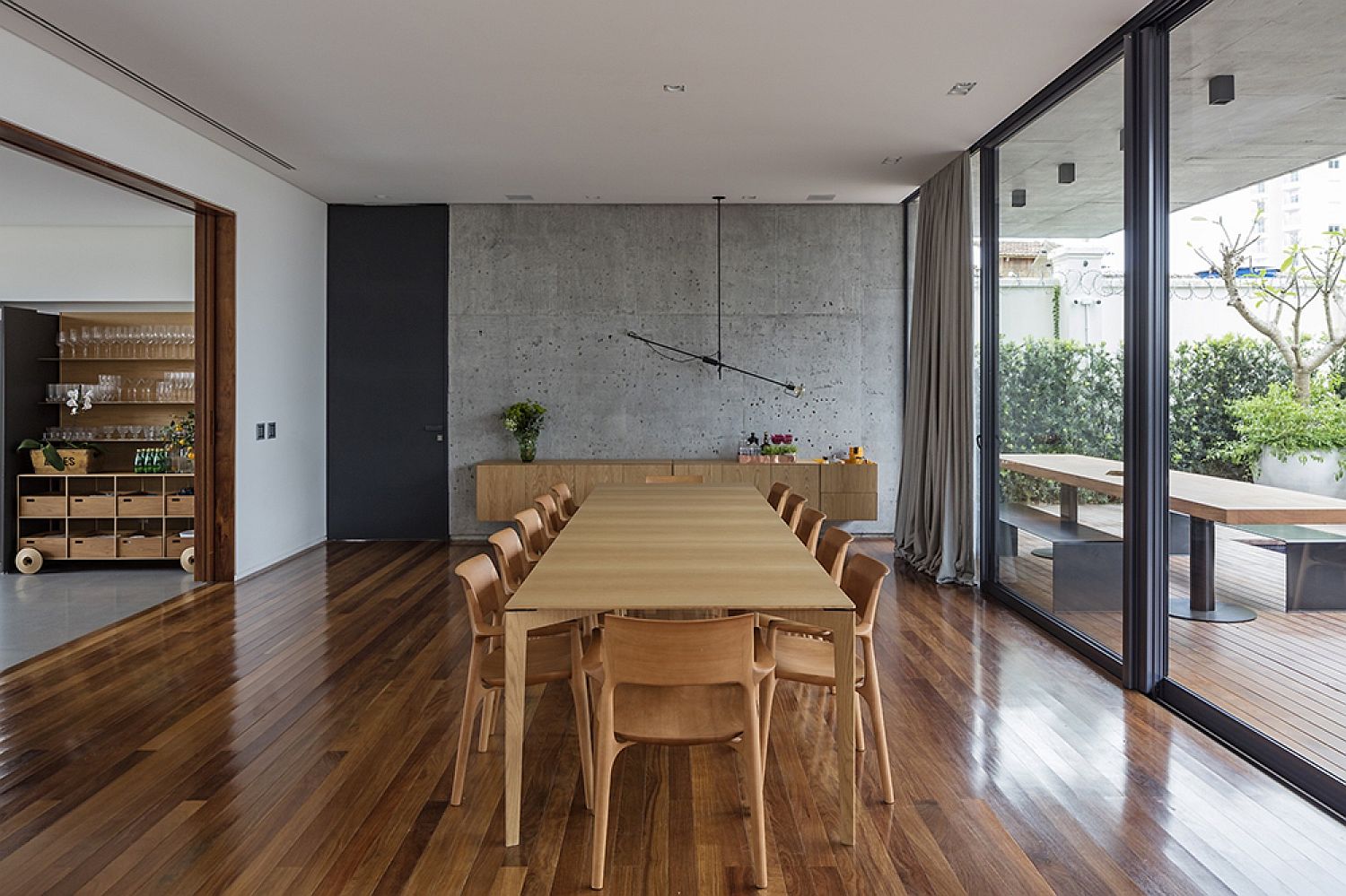 Spacious dining room with concrete and glass walls along with wooden flooring