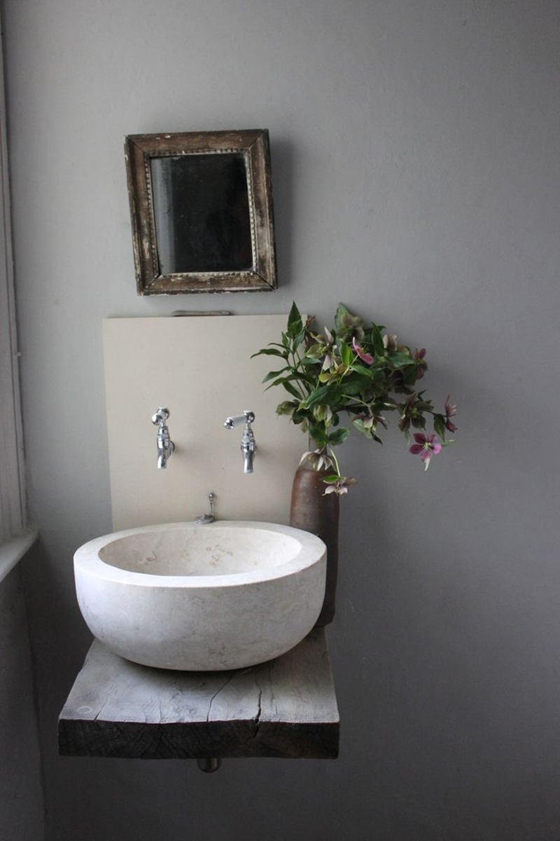 Stone vessel sink paired with an antique mirror and wooden surface