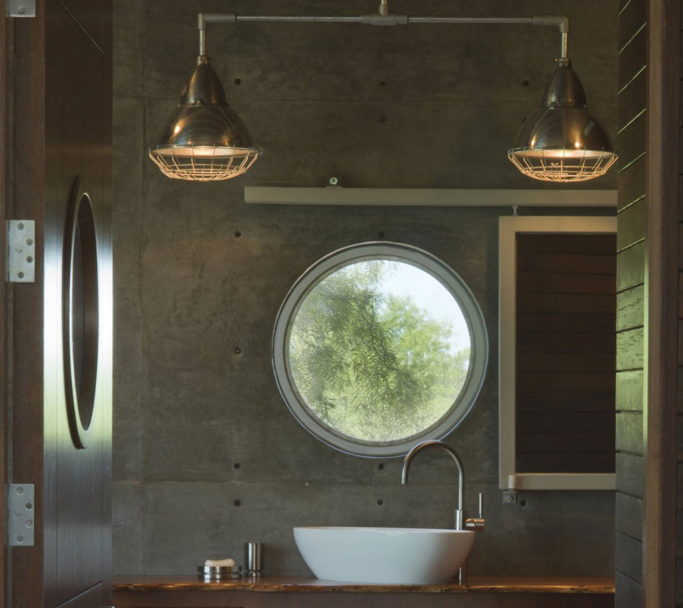 A concrete bathroom with a round window