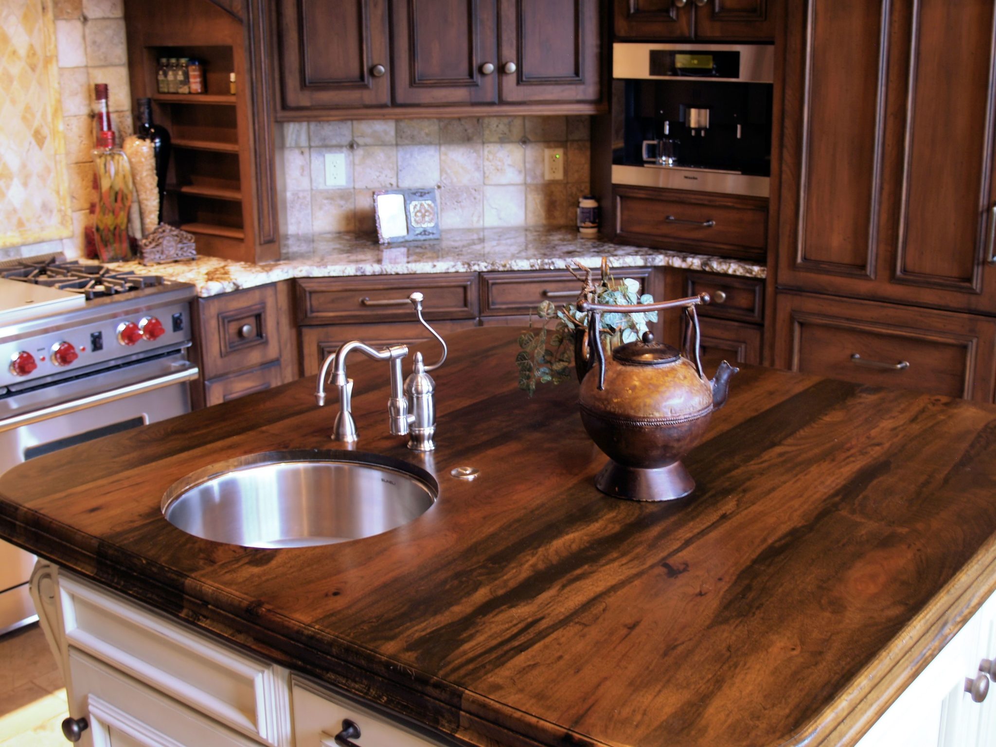 A kitchen island with a dark wooden countertop is the ultimate centerpiece