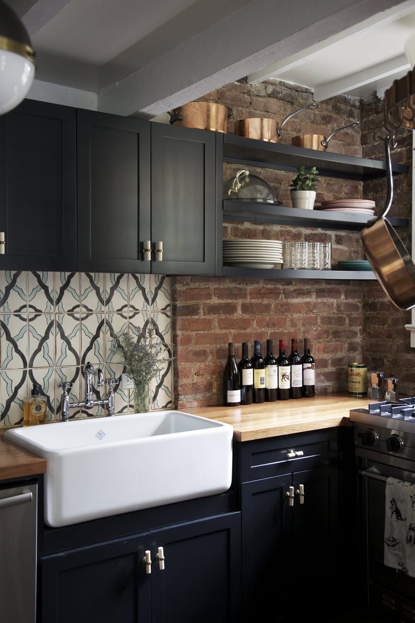 A kitchen with a striking dark interior and a light wooden countertop