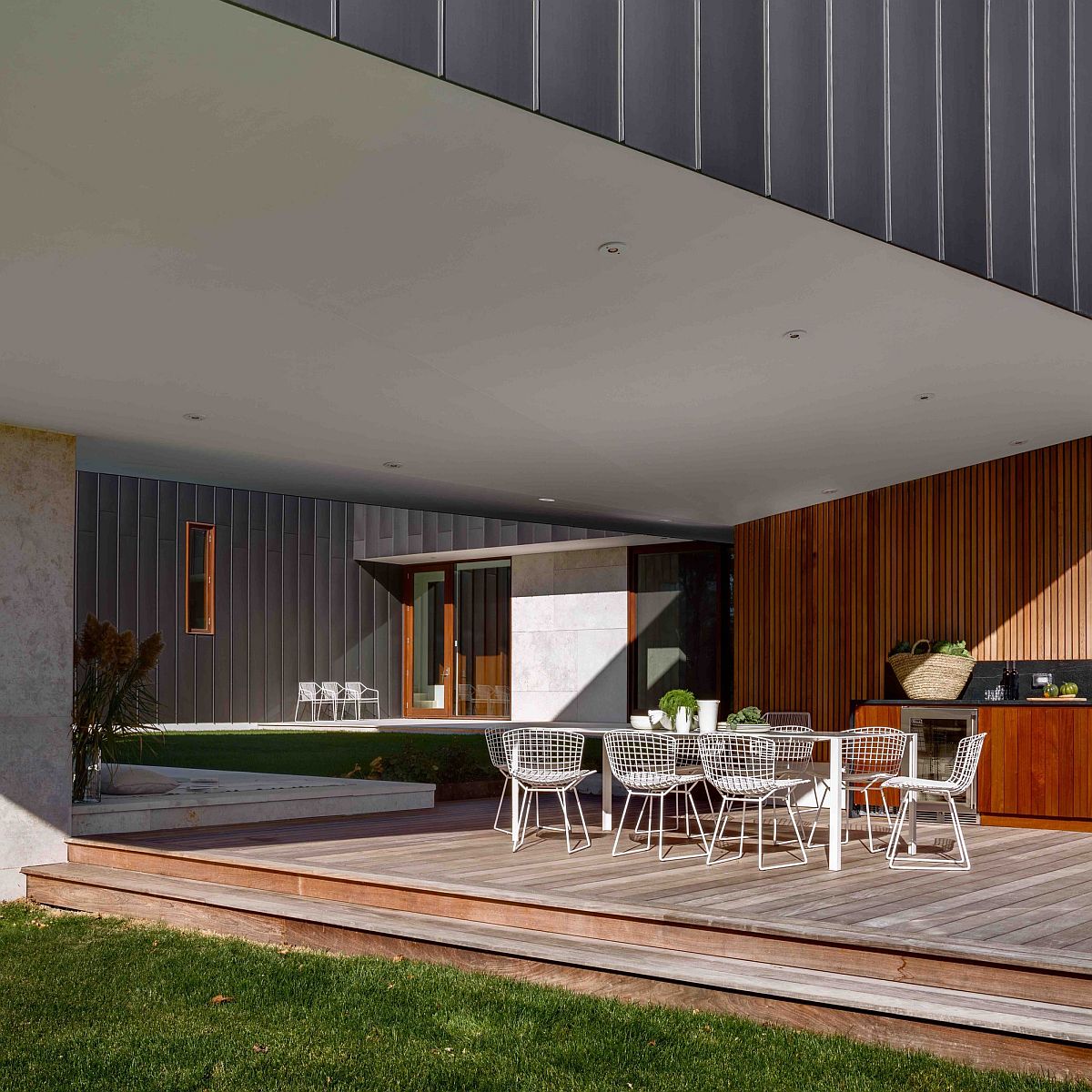 Cantilevered structure of the home offers shade for the outdoor dining and barbecue zone