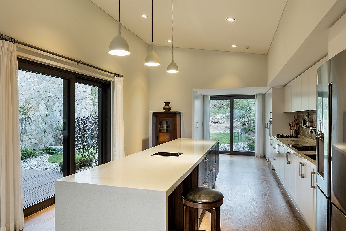 Large kitchen in white with a trio of pendants above the island