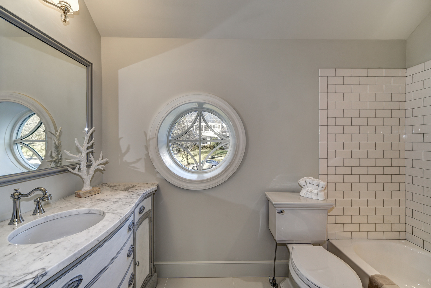 Modest round window in a classic white bathroom