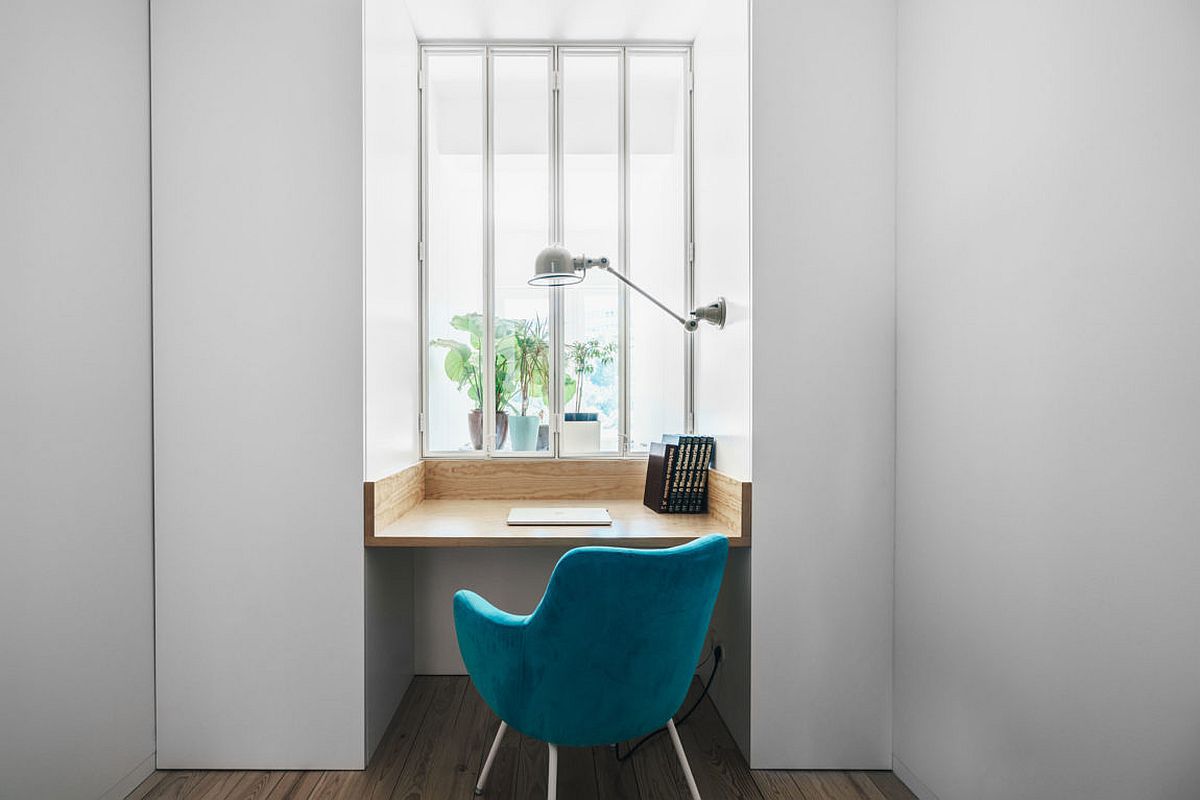 Small nook turned into home work area with wooden desk and bright blue chair