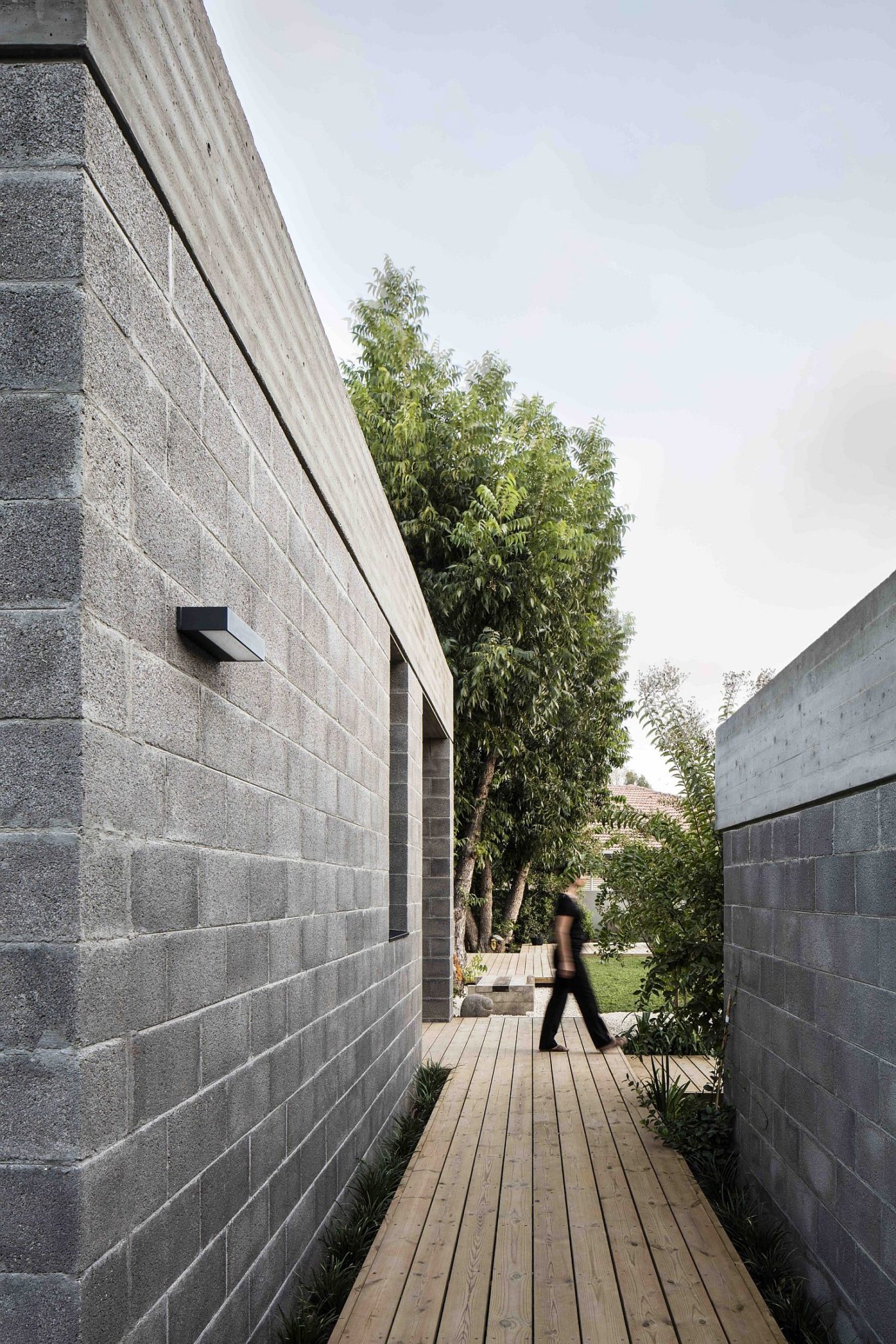 Wooden walkways and garden spaces surround the family house