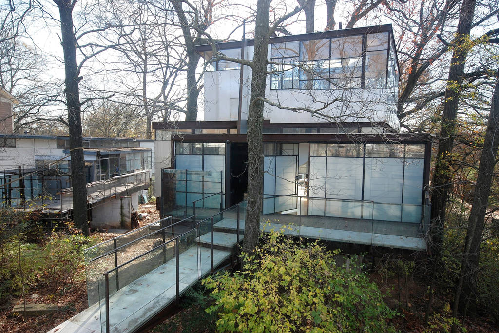 A glass treehouse with an open and illuminated interior