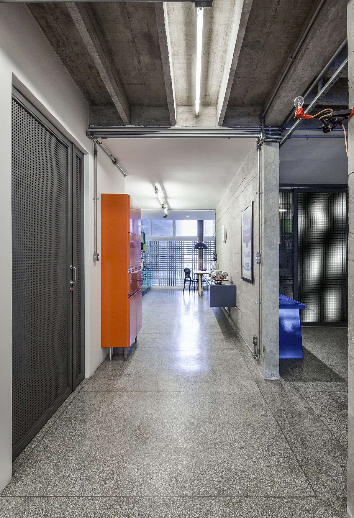 Orange cabinets and accents enliven the modern industrial interior