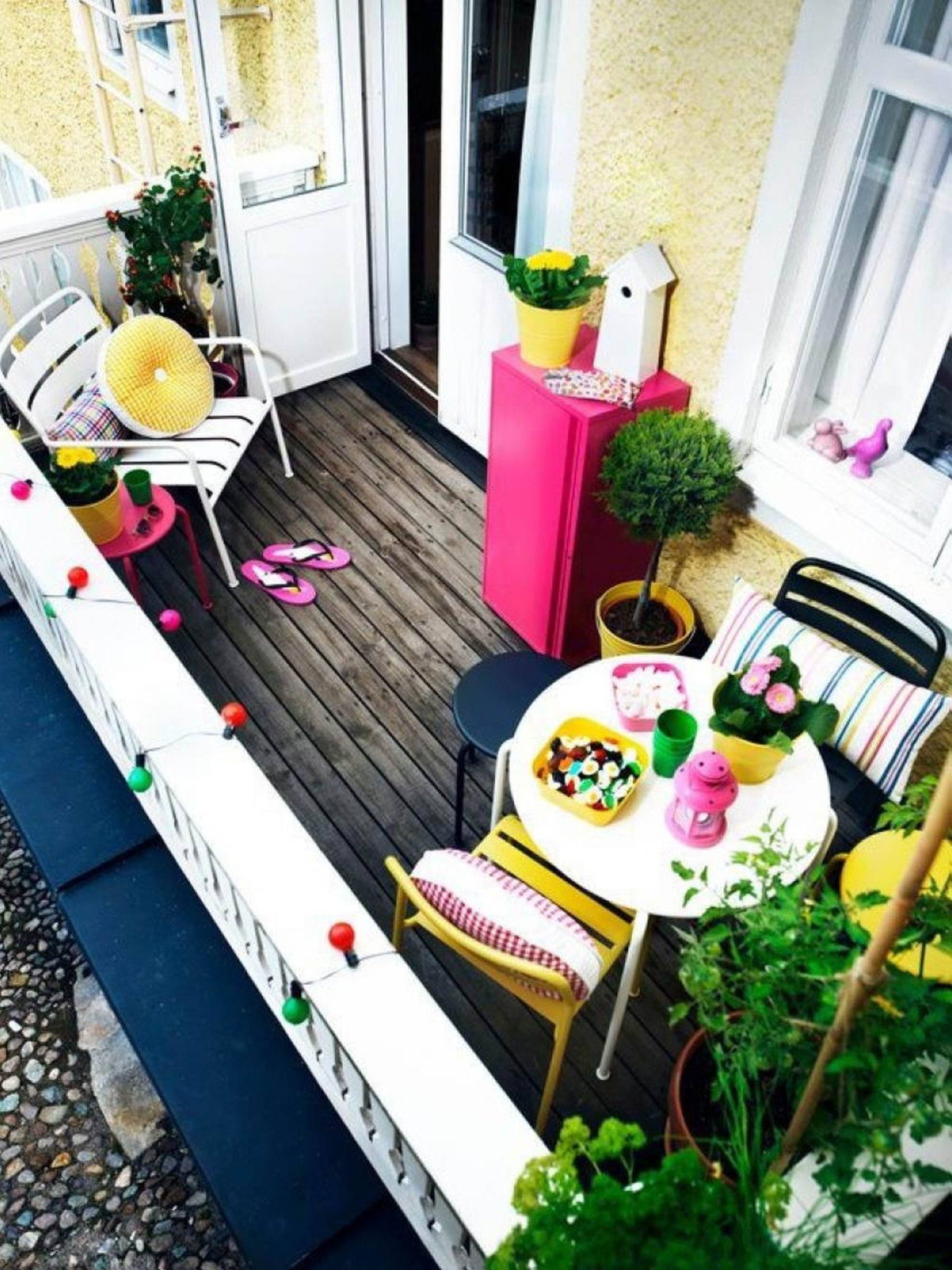 Tiny yellow balcony with a vibrant pink cupboard