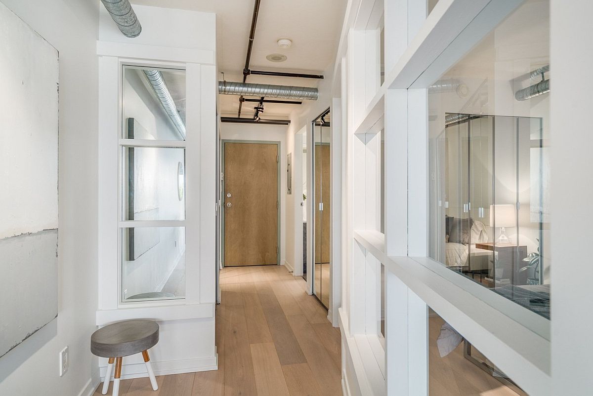 Folding, framed glass doors help delineate space inside the small loft apartment