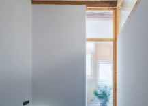 Small-bedroom-in-white-with-brick-ceiling-wooden-beams-and-sliding-translucent-glass-door-217x155