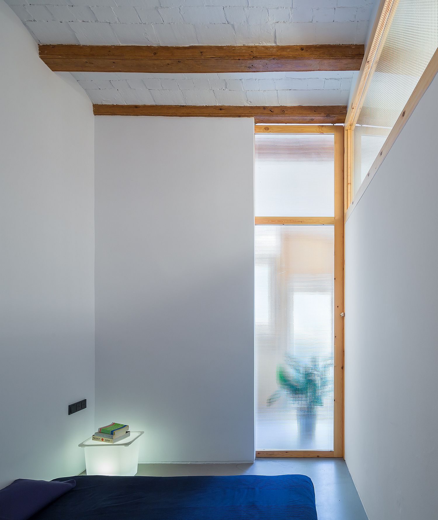 Small bedroom in white with brick ceiling, wooden beams and sliding translucent glass door