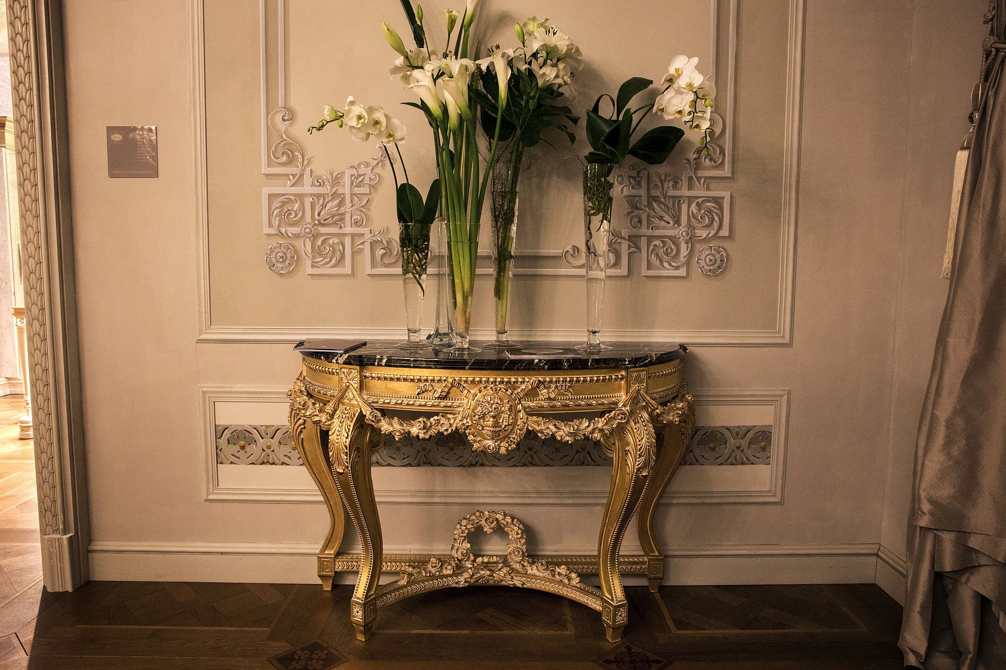 Tall glass vases with fresh flowers for the entryway console in gold and stone