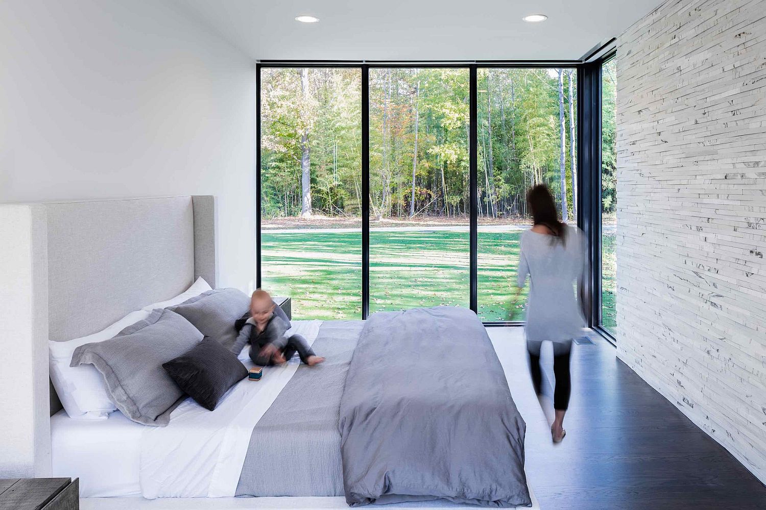 Contemporary bedroom in white with stone accent wall