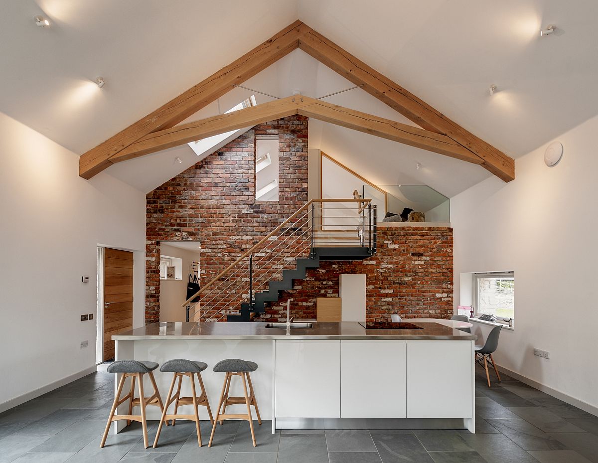 Gorgeous brick wall provides a beuatiful backdrop for contemporary kitchen in white