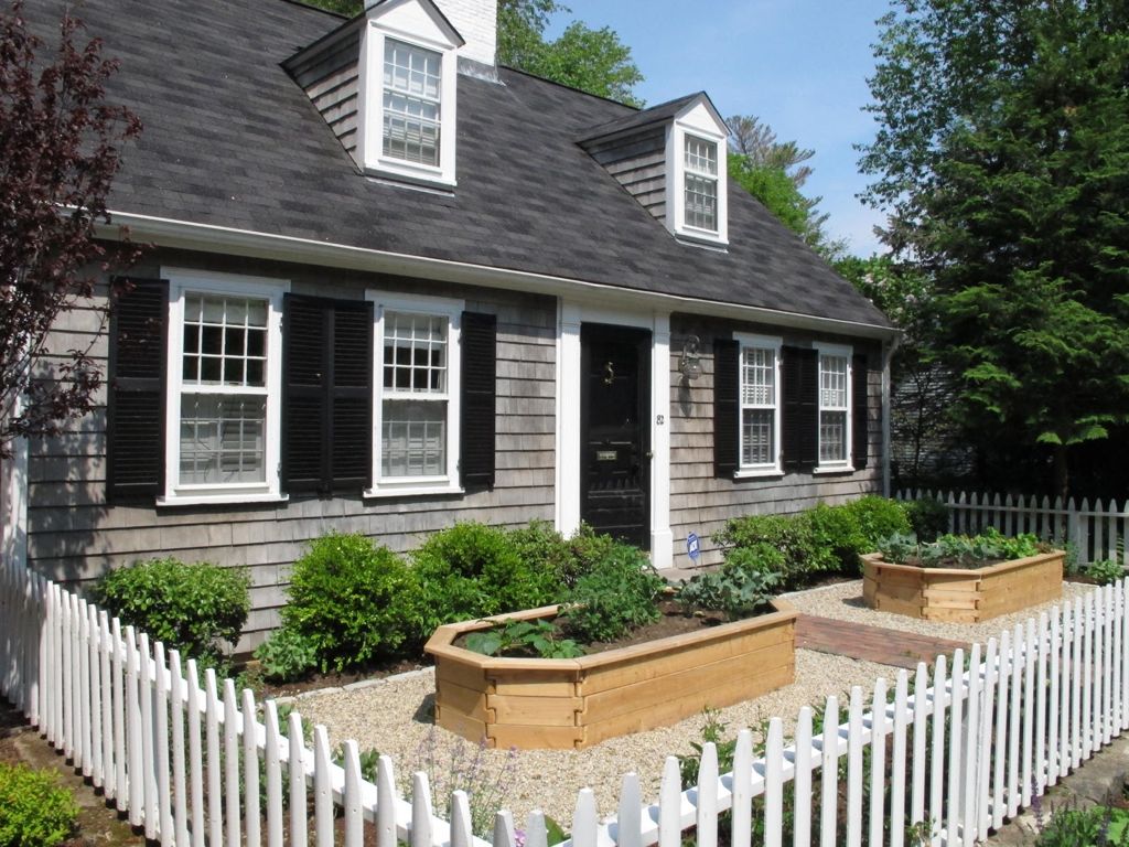 Home with a dark exterior and a white picket fence