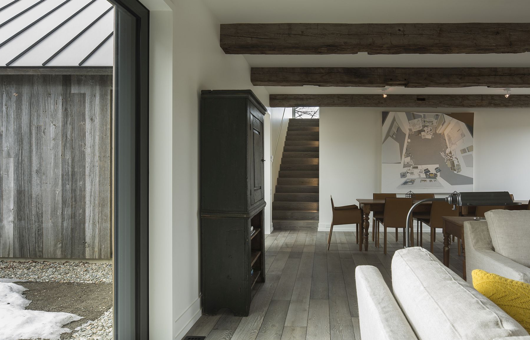 Large windows, exposed wooden beams and a neutral color palette shape the living area