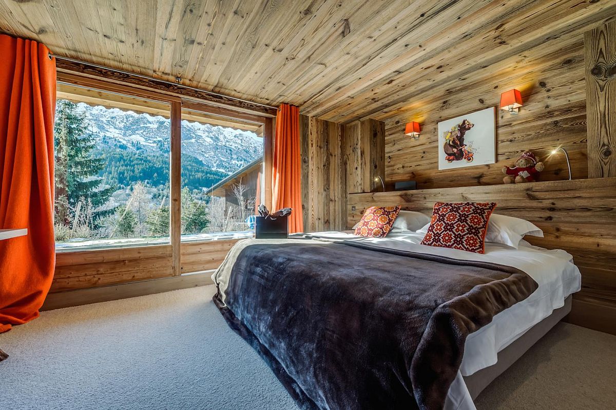 Pops of orange brought in by drapes and sconce lights into the woodsy bedroom