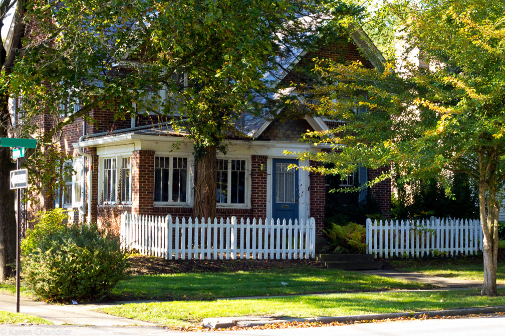 Red brick house with a charming white picket fence