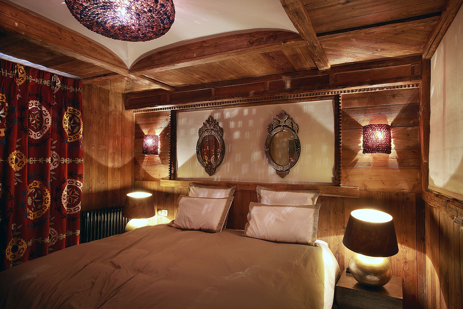 Sconce lighting along with chandelier and bedside lights in the comfy bedroom