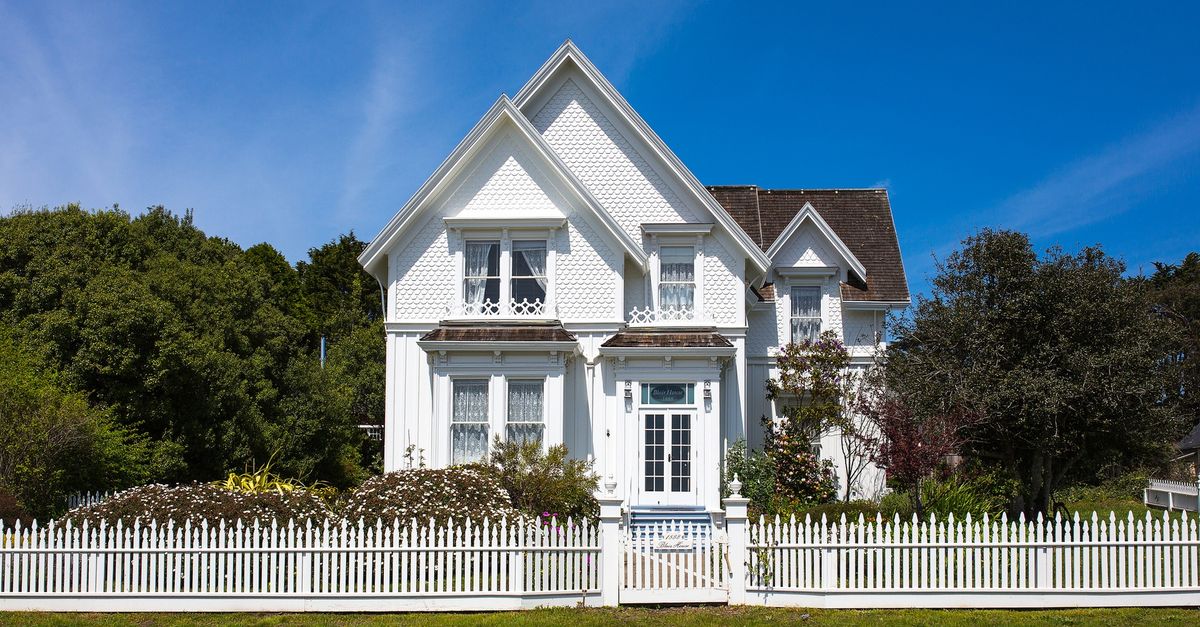 Tall victorian house with a vintage white picket fence