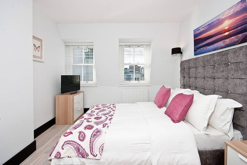 Comfortable bedroom in white with a tufted headboard wall and pops of purple