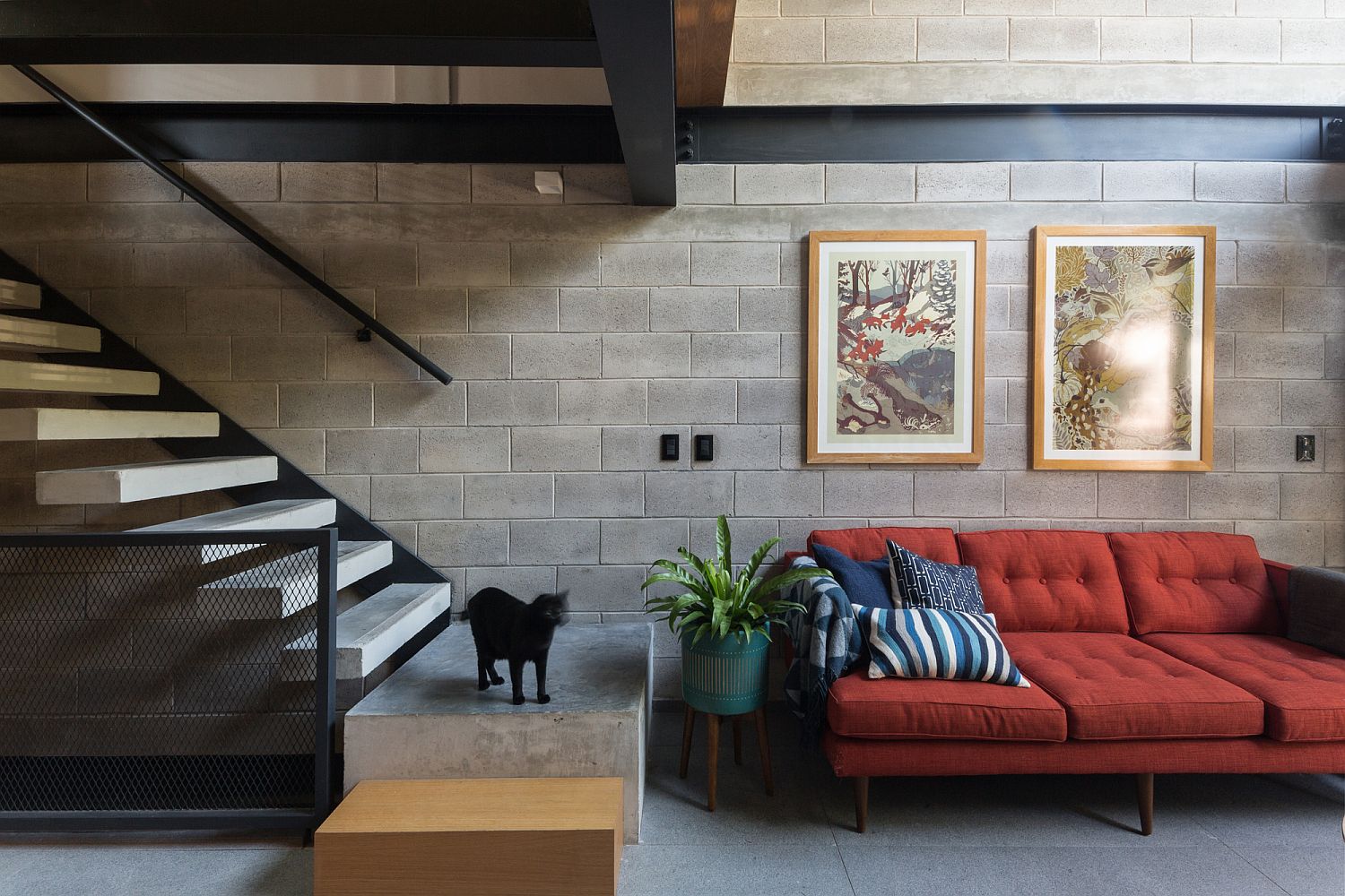 Concrete backdrop of the living area with a couch in bright red