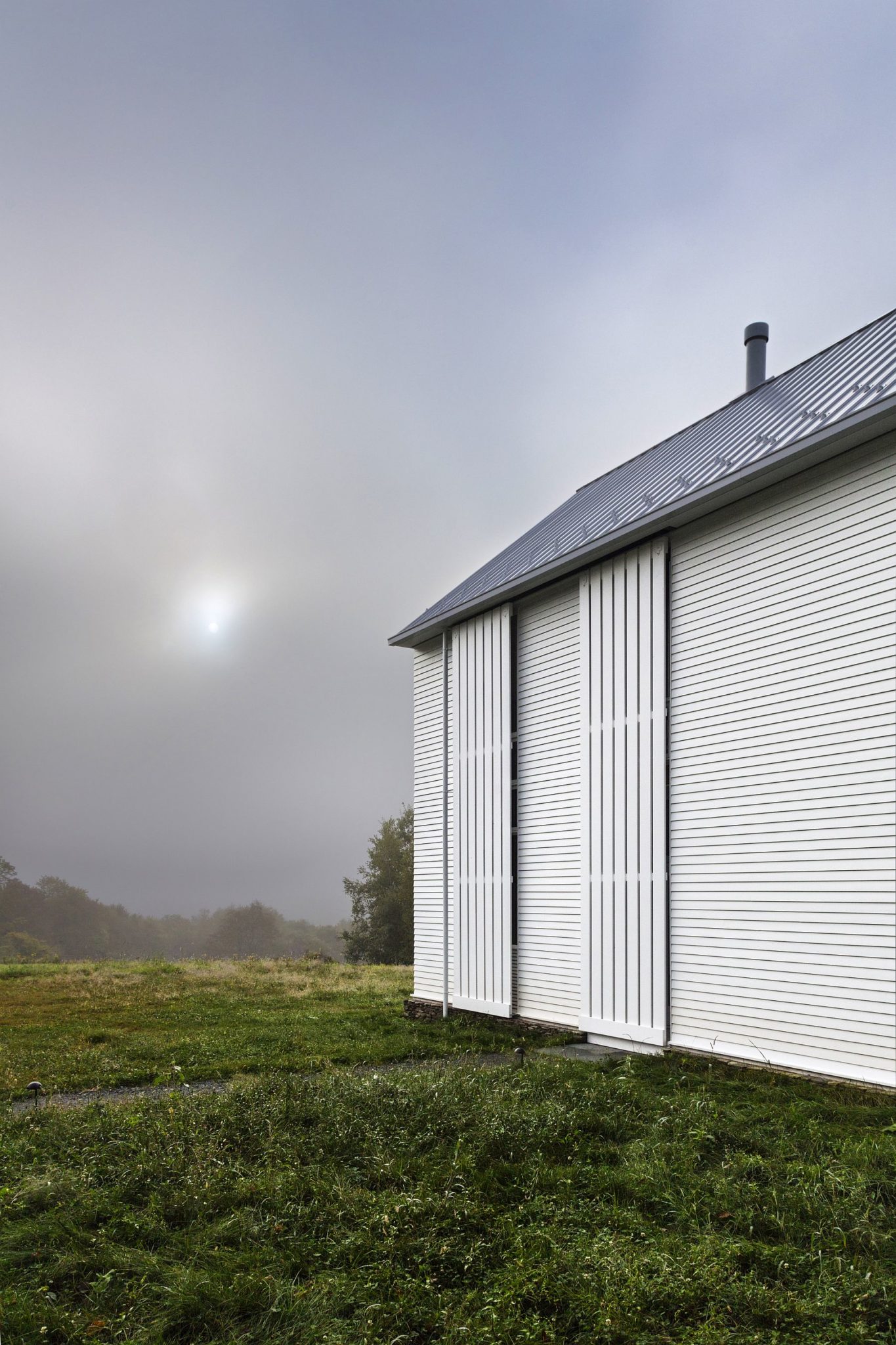 Rolling screens in white shape the exterior of the farmhouse style contemporary home