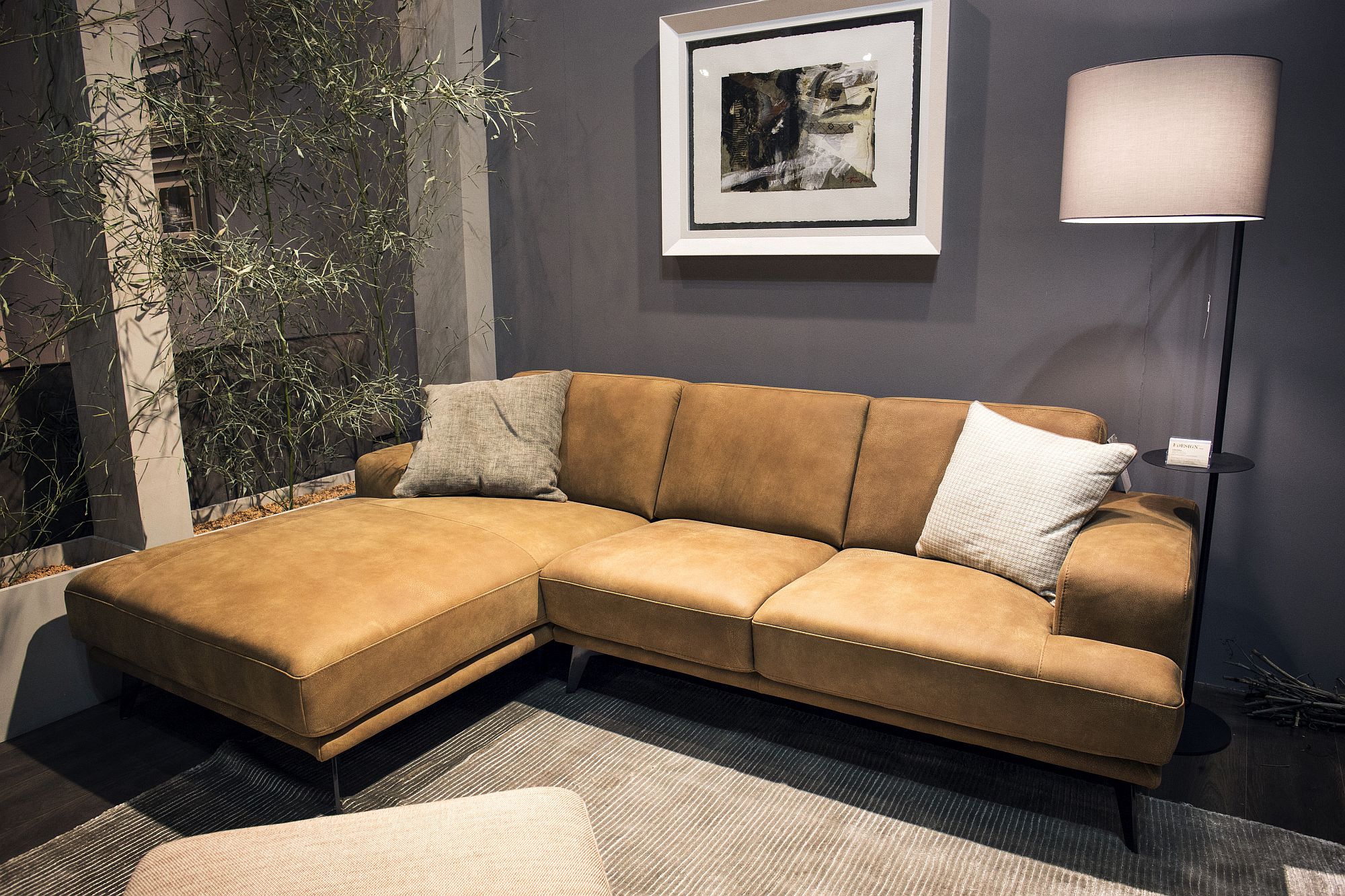 Slim floor lamp in the corner with a large brown sectional next to it