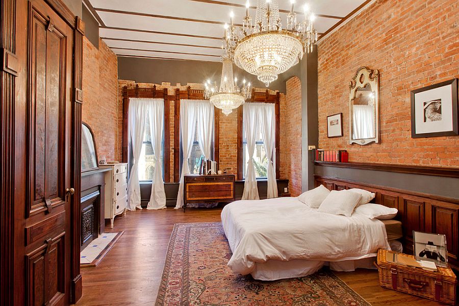 Spacious brick walled bedroom with twin chandeliers