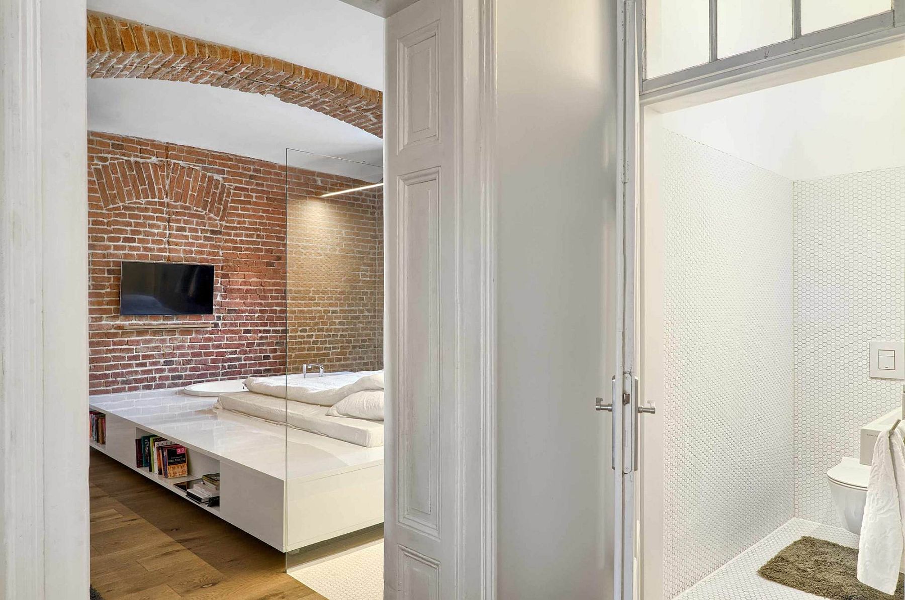 Stunning bedroom in white with brick walls inside the apartment of a football player