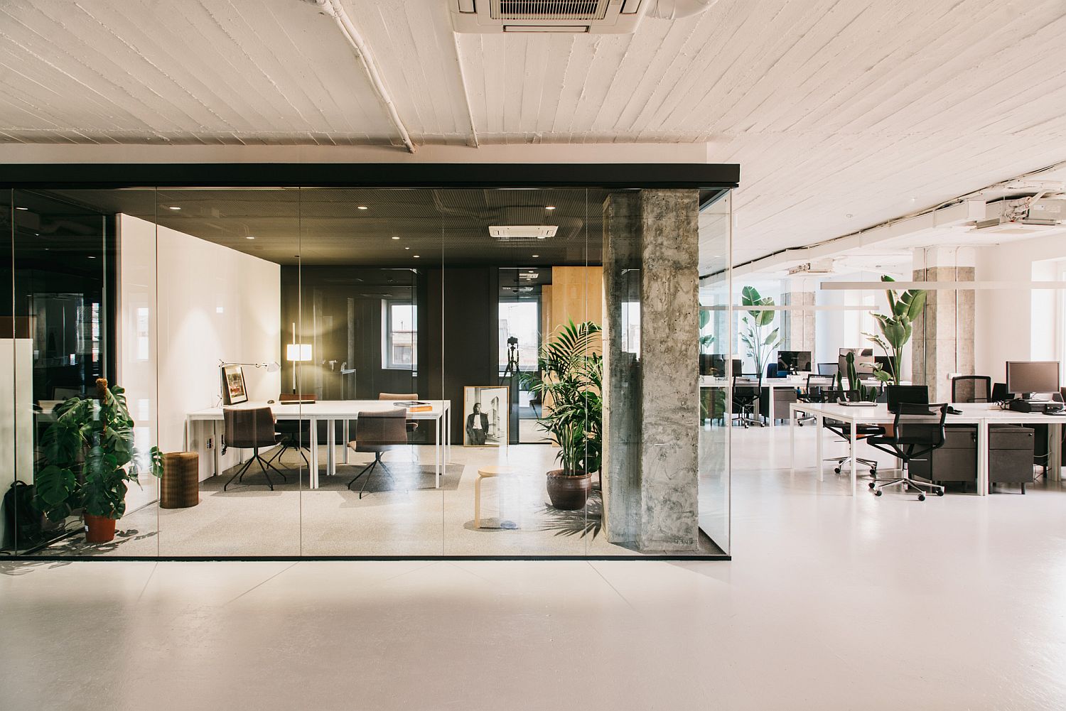 Exposed concrete pillars and glass walls shape the private office spaces