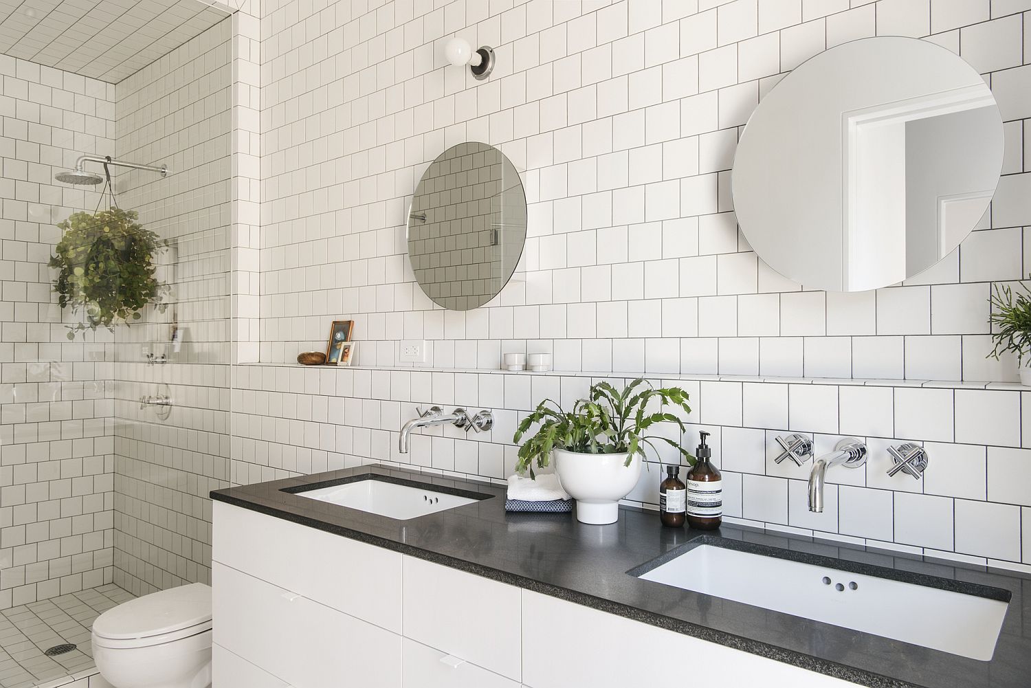 Polished-modern-bathroom-in-white-with-twin-mirrors-and-tiled-walls